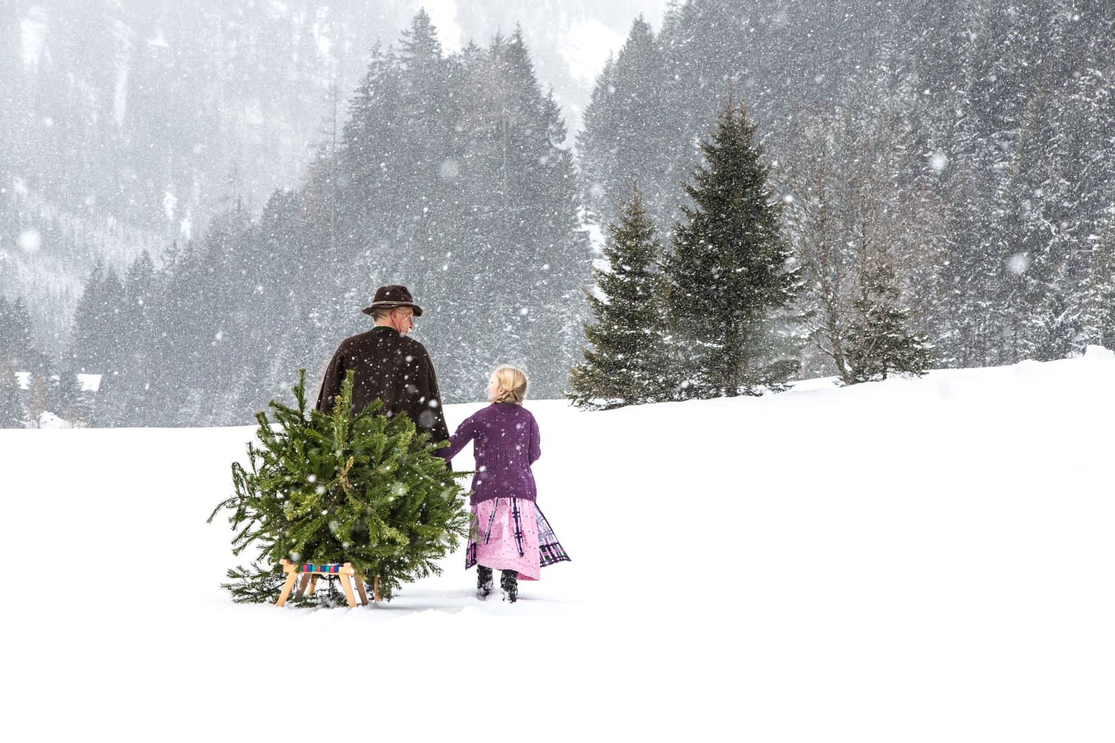 Mann zieht Tannenbaum auf Schlitten durch Schnee